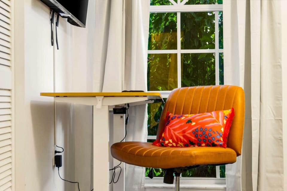 Bright and comfortable queen bedroom with TV, desk, and cozy workspace—ideal for rest or remote work.