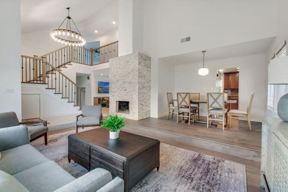 This beautifully decorated living room features an elegant chandelier, a cozy fireplace, and a modern dining area.