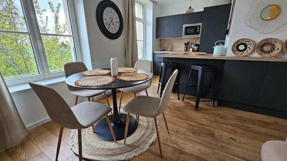 Espace salle-à-manger dans le salon, avec une table et quatre chaises, ouvert sur la cuisine.