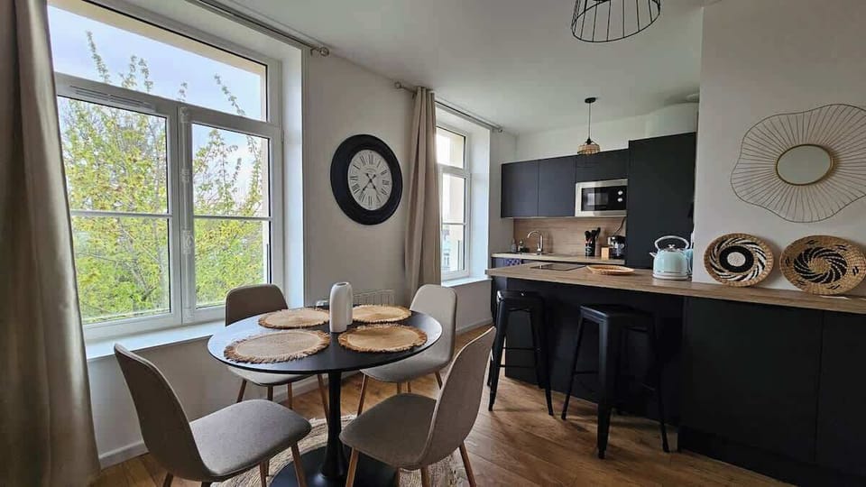Espace salle-à-manger dans le salon, avec une table et quatre chaises, ouvert sur la cuisine. 