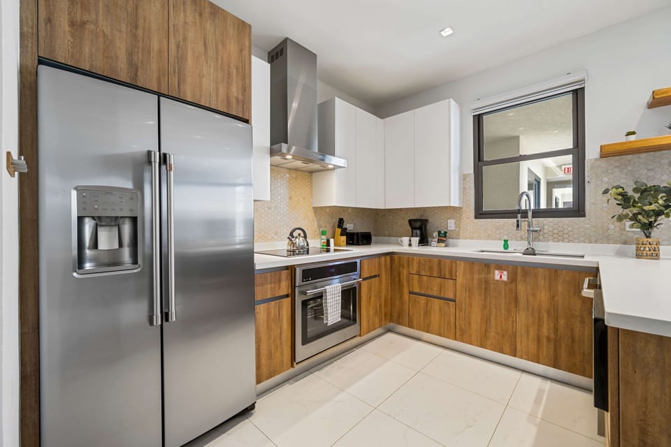 - Cook with ease in this sleek kitchen featuring stainless steel appliances and warm wood cabinetry - Bright and airy with plenty of counter space, perfect for creating culinary delights - A harmonious blend of style and practicality