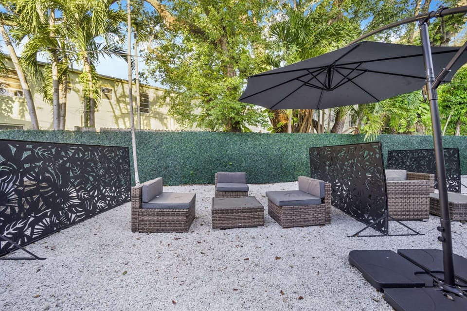 Seating area with chairs, fence, umbrella, and tree shade