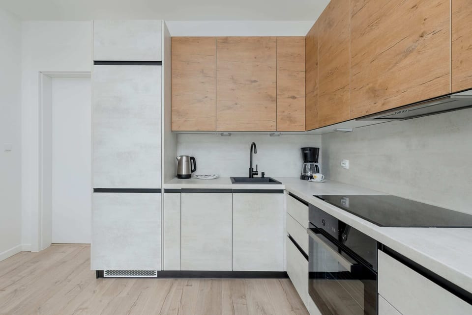 A well-organized kitchen area featuring a dishwasher and induction cooktop. Wooden finishes add a cozy touch.