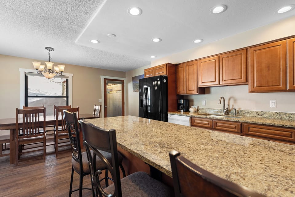 Gather around this spacious kitchen island where warm wood cabinets and granite counters create the perfect spot for morning coffee and evening conversations.