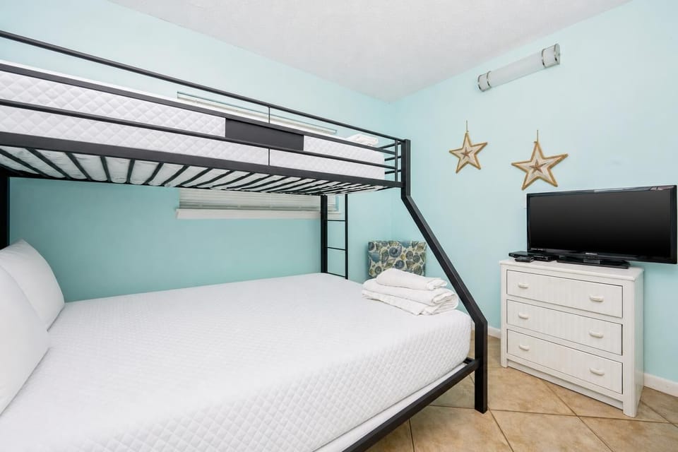 This guest room features a bunk bed, a comfortable double bed, and a TV, perfect for family or friends to relax together