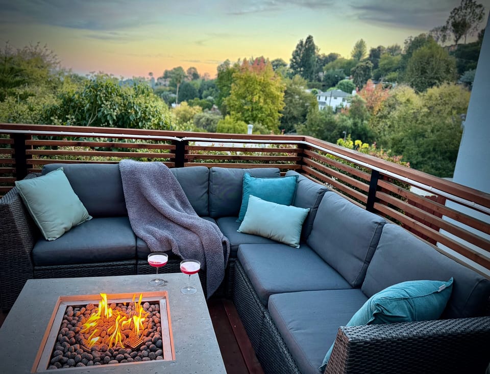 Cozy up by the fire table with drinks and treetop views at golden hour