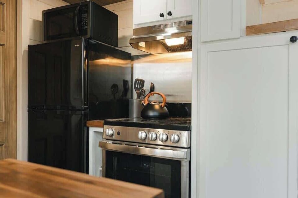 The kitchen with farmhouse sink, butcher block counter tops, full stove / oven and apartment-sized fridge + freezer.
