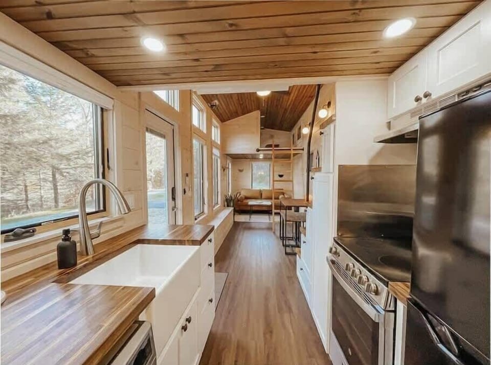 The kitchen with farmhouse sink, butcher block counter tops, full stove / oven and apartment-sized fridge + freezer.