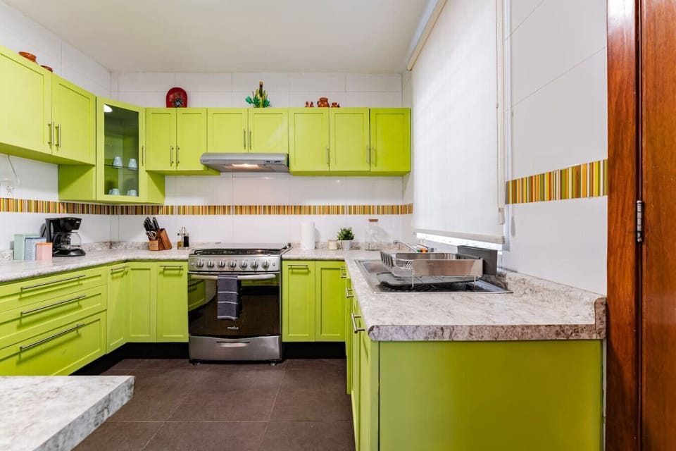 Fully equipped kitchen with unique retro green cabinetry and modern appliances.