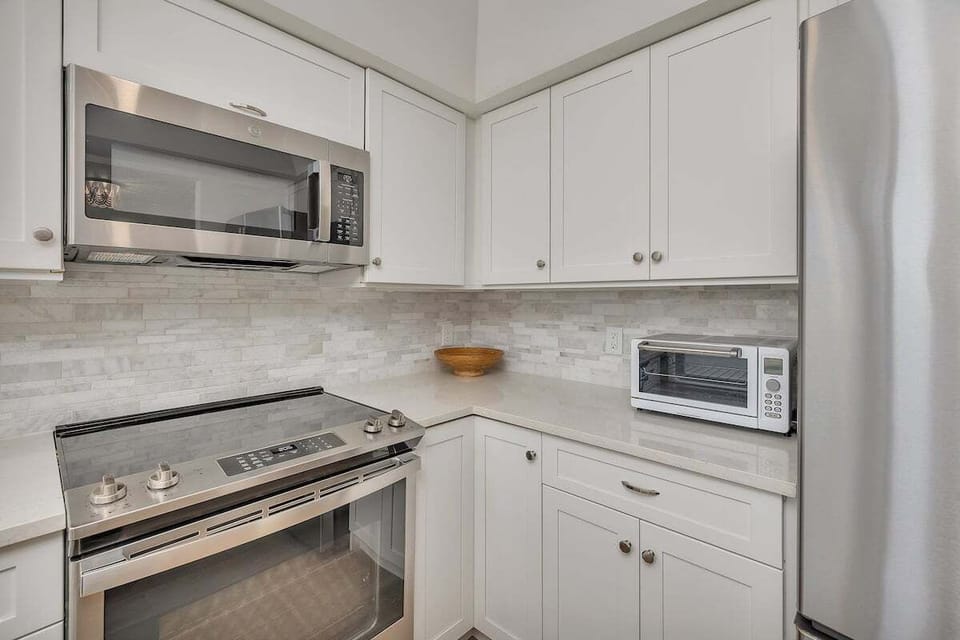 Kitchen with white cabinets, stainless appliances, and tile backsplash