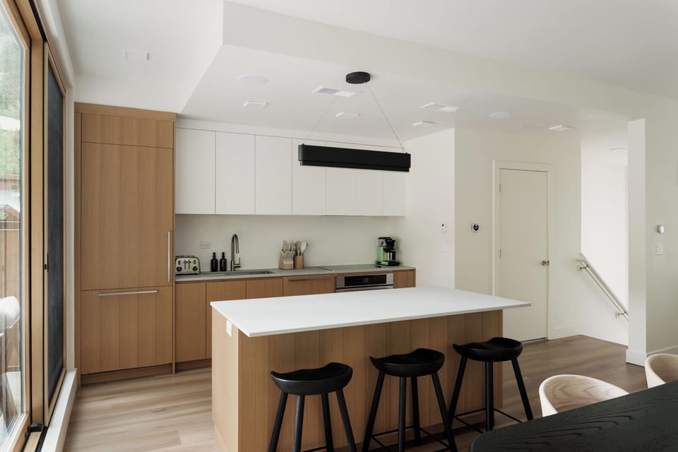 Sleek kitchen with island seating and wide glass doors opening to the deck.