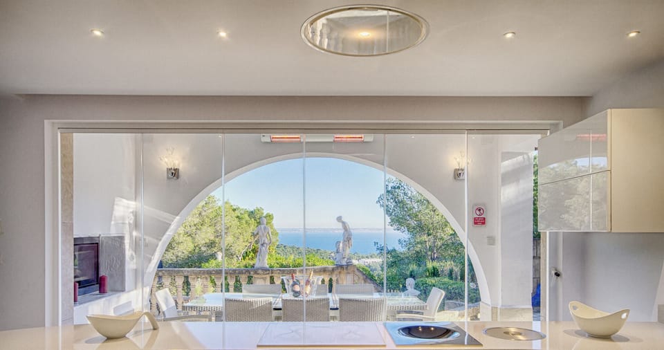 Modern kitchen with island and panoramic sea views at Villa Ocean View, Portals Nous. Bright space with terrace access.