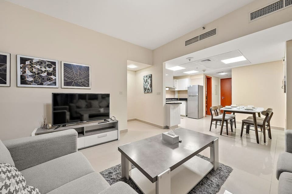 Modern open-plan space with TV lounge, dining area, and kitchen entrance.