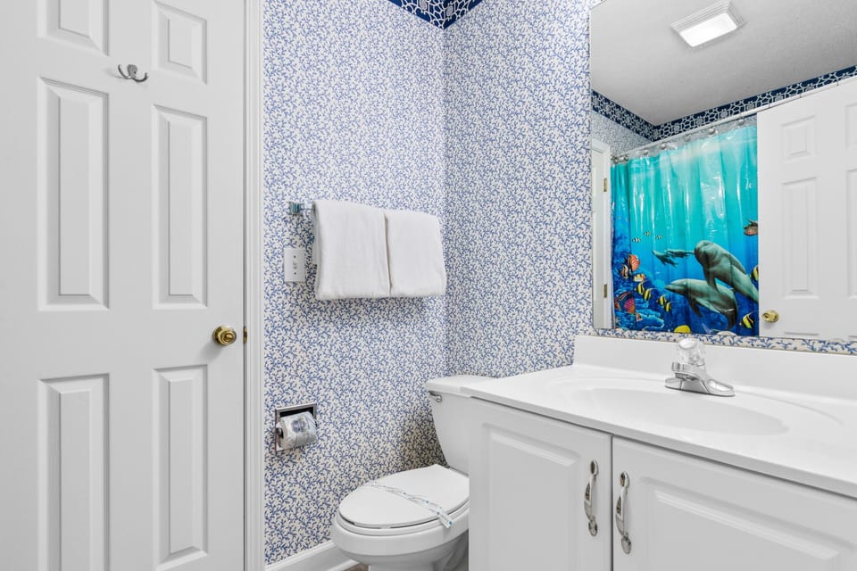 Dive into relaxation in this ocean-themed bathroom featuring vibrant marine life artwork and sparkling blue mosaic walls.