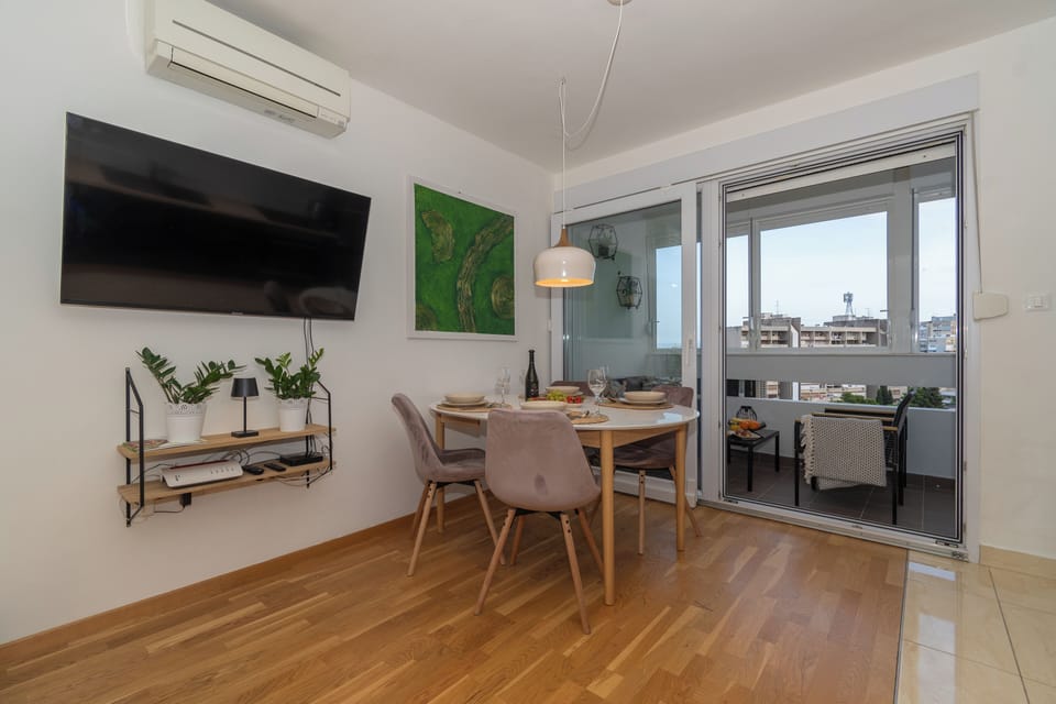 Dining area with balcony view, green accents, and a fresh natural feel.
