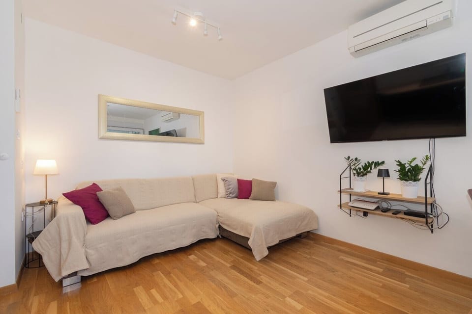 Bright living room with soft tones and a large modern TV screen.
