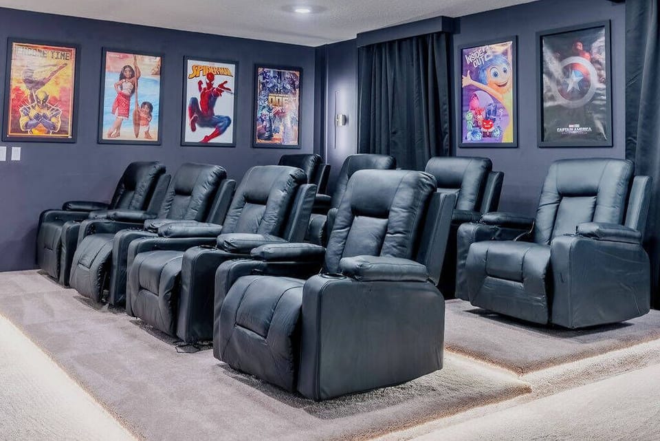 Enjoy cinematic comfort in this home theater with plush black reclining chairs designed for an immersive experience. Vibrant movie posters enhance the cozy atmosphere, inviting you to relax and enjoy your favorite films.
