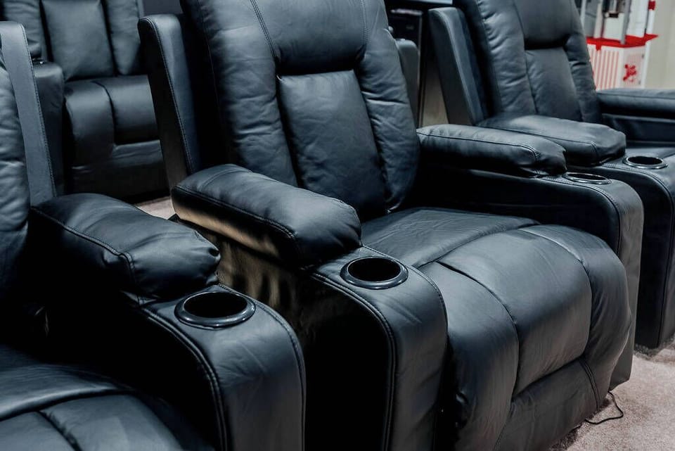 Experience ultimate comfort in this cozy home theater, featuring plush black recliners designed for relaxation. Each chair is equipped with cup holders, ensuring your movie nights are both enjoyable and convenient.