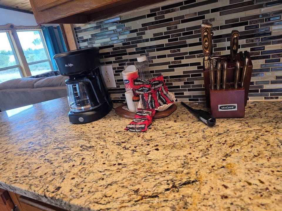 Coffee station stocked with a coffee maker and grounds, plus a full knife block.