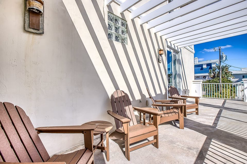 The second-floor balcony features Adirondack chairs, perfect for relaxing and soaking up the Florida sun.