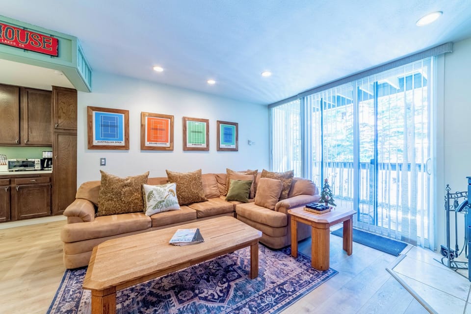 Living room has nice sized deck overlooking pine trees.