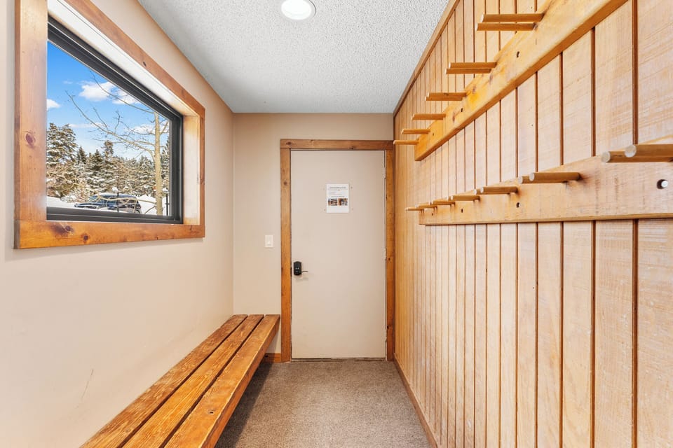 Warm wood details welcome you inside, with a cozy bench for boot removal and stairs leading to your mountain retreat.
