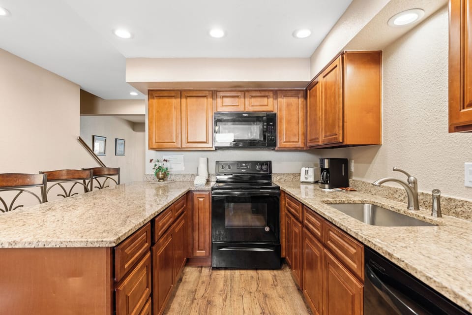 Your fully equipped kitchen awaits with warm wood cabinetry, granite countertops, and modern appliances for creating memorable meals during your stay.