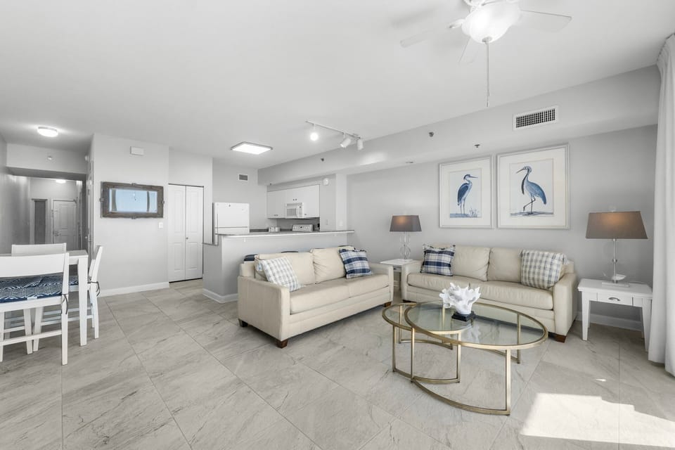 Bright living room w/ plush seating, glass coffee table & gorgeous natural light.