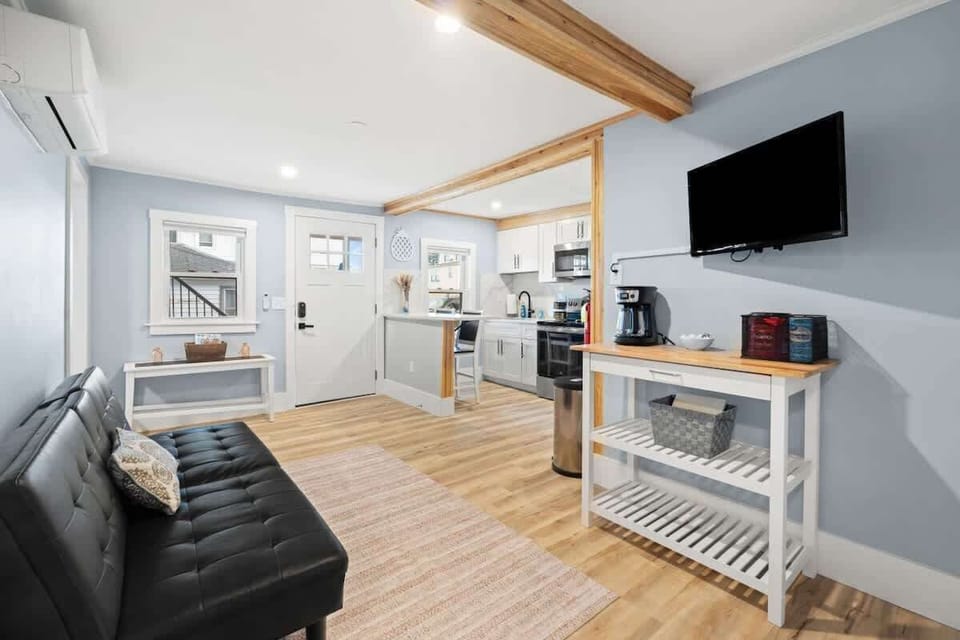Relax in this sun-filled living area with a comfy futon, smart TV, and a stocked coffee bar. Modern finishes and wood accents create a cozy vibe.