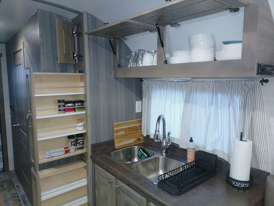 Slide out pantry with grilling seasonings. Plates, bowls and glasses & cups .