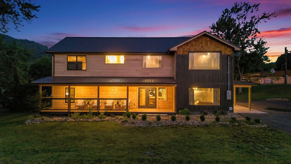 Modern cabin exterior glowing at dusk, featuring inviting outdoor seating.