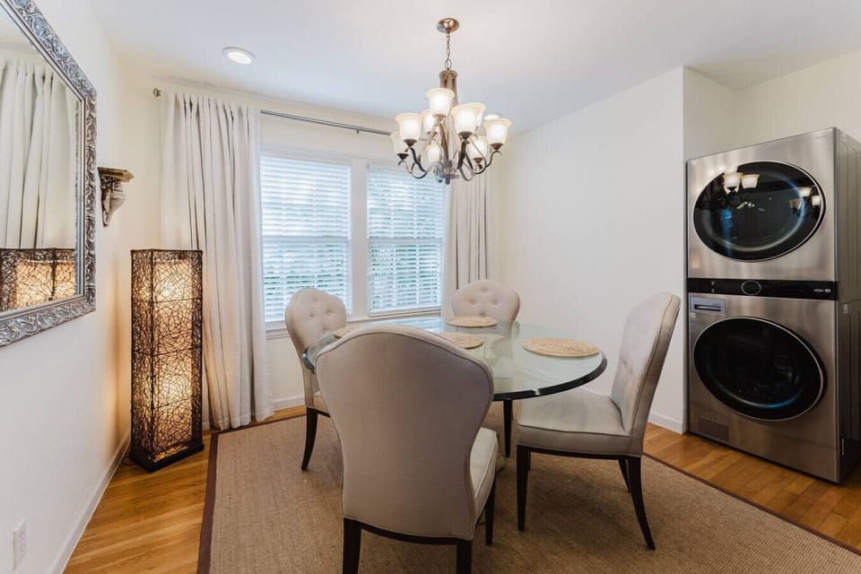 This stylish dining area features a cozy glass-top table, elegant lighting, and the convenience of in-unit laundry for a comfortable and functional space.