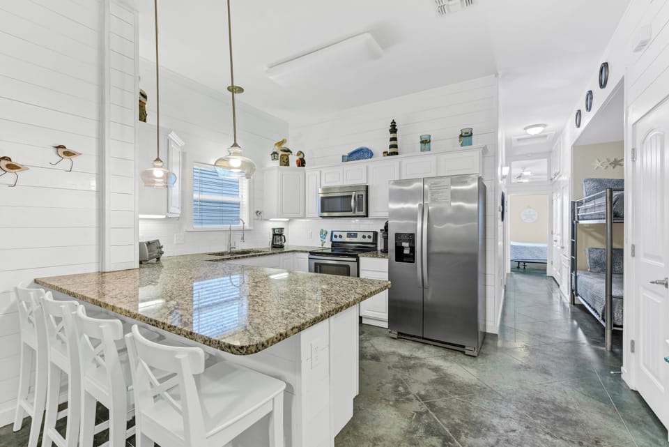 Your bright coastal kitchen features granite countertops, stainless steel appliances, and charming nautical touches that make meal prep feel like a seaside escape.