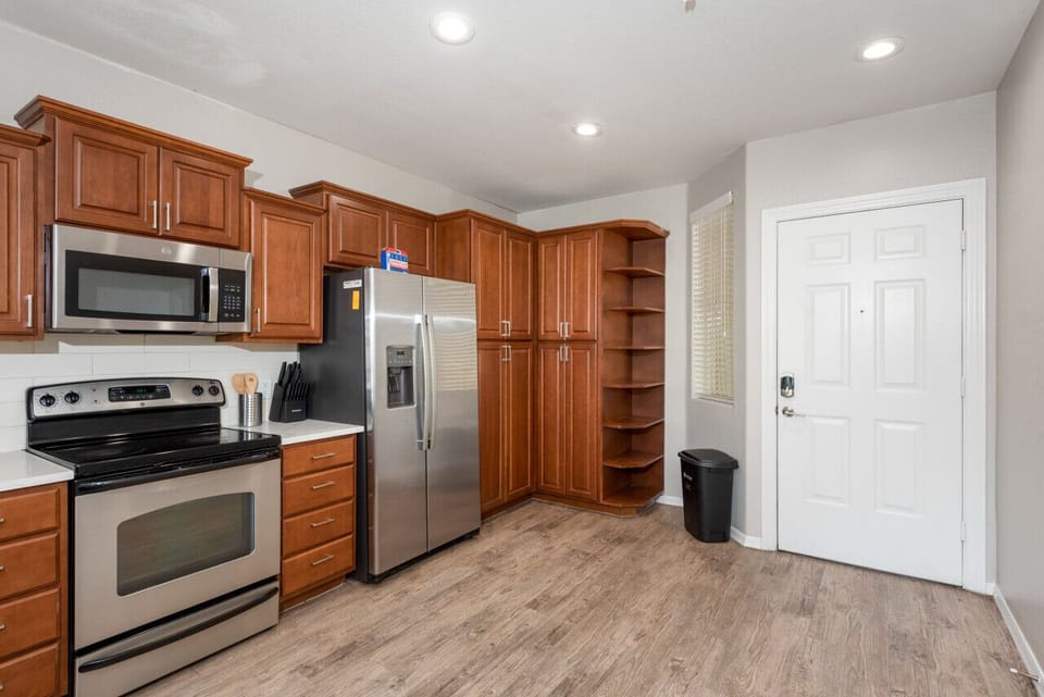 Modern functional kitchen with microwave, fridge, stove and basic cooking ware