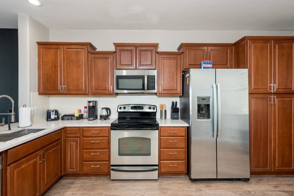 Modern functional kitchen with microwave, fridge, stove and basic cooking ware