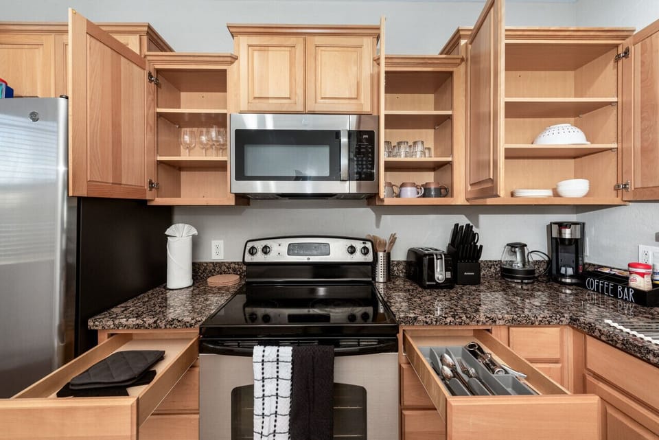Modern functional kitchen with microwave, fridge, stove and basic cooking ware