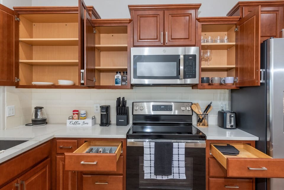 Modern functional kitchen with microwave, fridge, stove and basic cooking ware