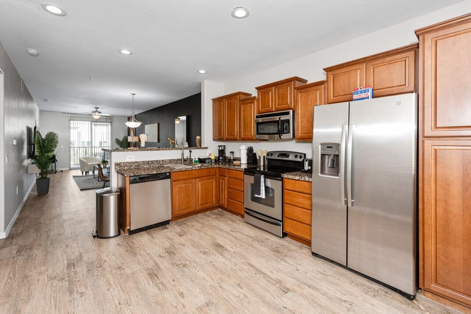Modern functional kitchen with microwave, fridge, stove and basic cooking ware