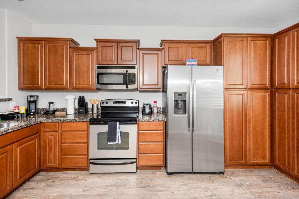 Modern functional kitchen with microwave, fridge, stove and basic cooking ware