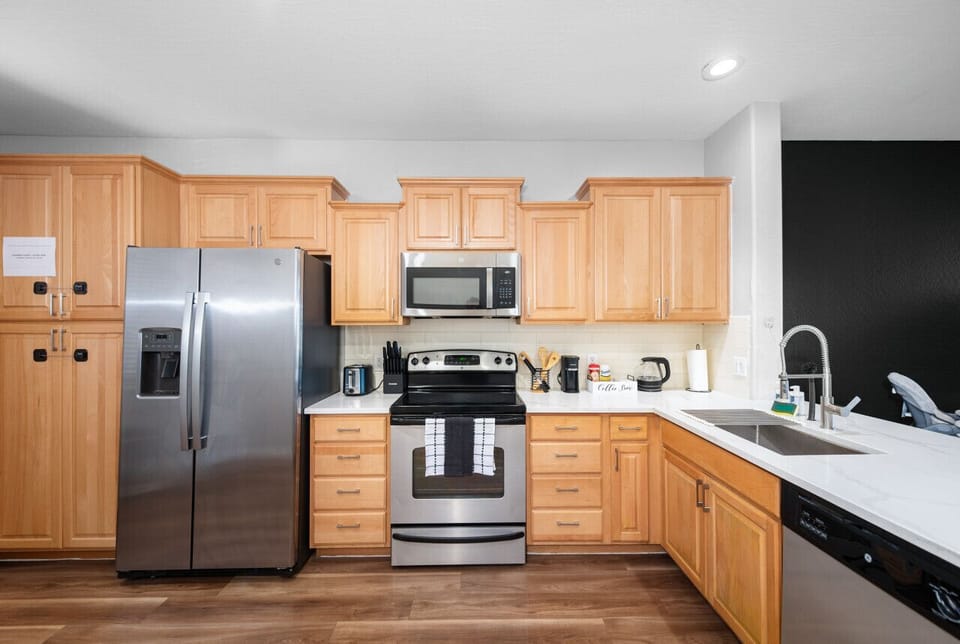 Modern functional kitchen with microwave, fridge, stove and basic cooking ware