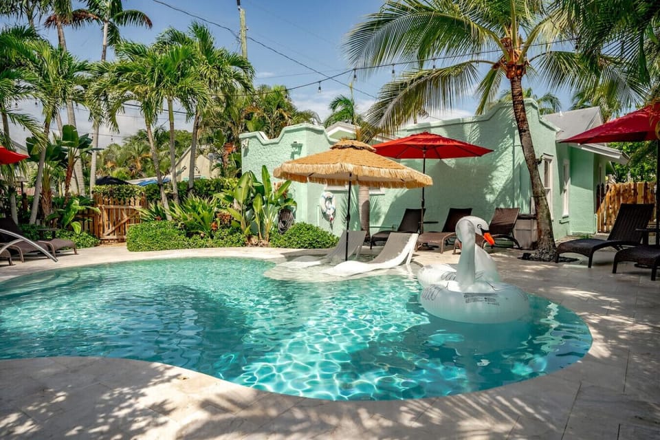 Relax by the sparkling turquoise waters, surrounded by lush tropical palms and vibrant umbrellas for a refreshing day in paradise.