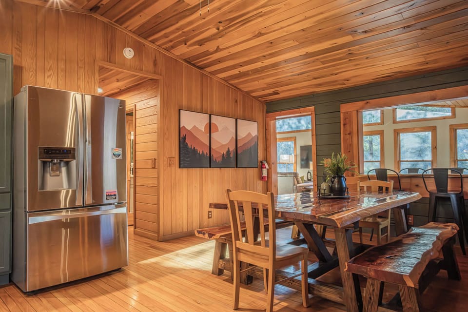 Live-edge dining table with bench seating, bar, and cozy rustic decor.