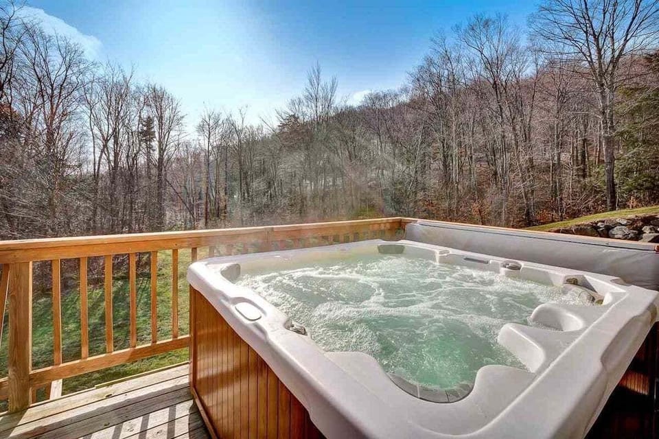 Step onto the deck for a soak while the wooded hillside fills the view beyond the railing.