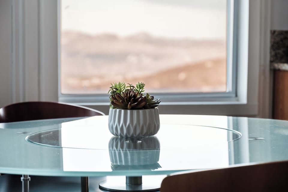 Round glass dining table with seating for four, perfect for quick breakfasts, takeout nights, and board games, with mountain scenery just outside the window.