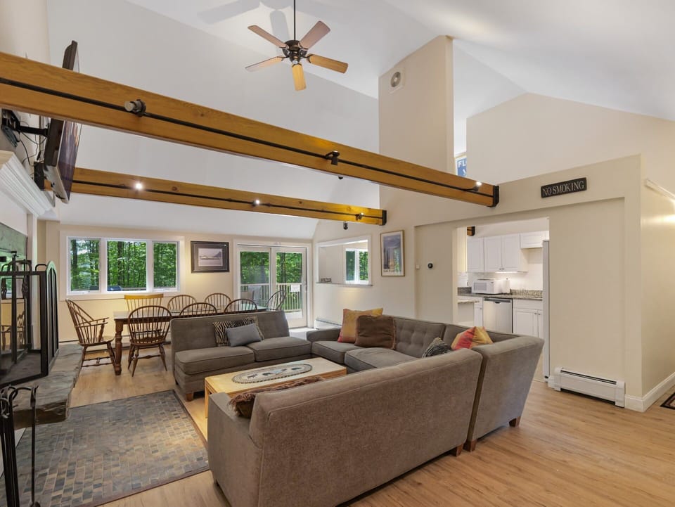 Spacious open floor plan with comfortable U-shaped seating, a wood-burning fireplace, a dining table and breathtaking mountain views.