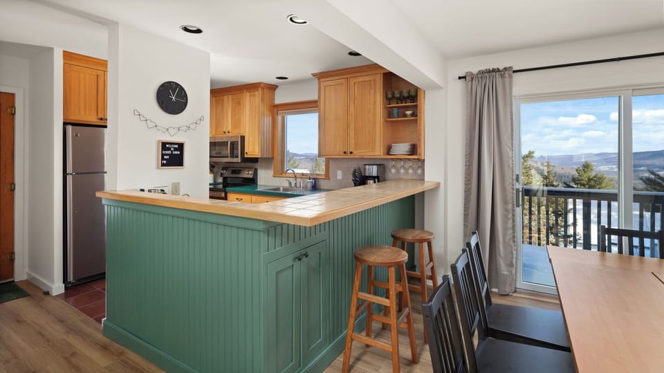 - Kitchen with wood cabinetry and stainless steel appliances   - Window above sink with scenic mountain and forest views   - Fully equipped space for convenient home-style cooking