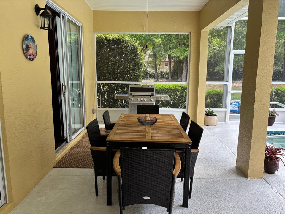 Covered lanai area with gas grill, table & chairs, and loungers. 