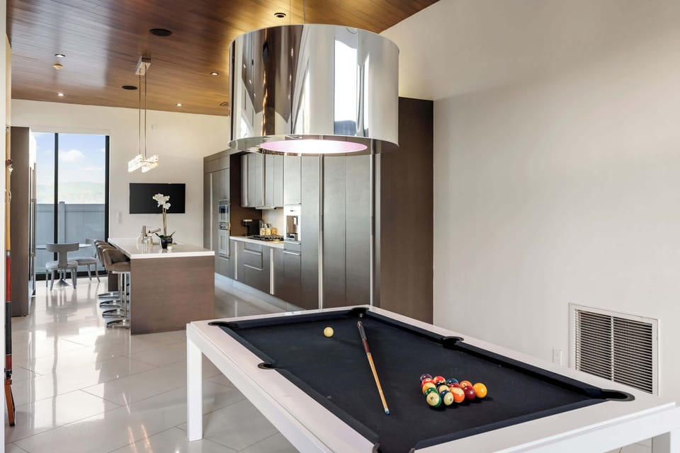 Game Room: Pool Table with Chrome Pendant Light & Kitchen in Background