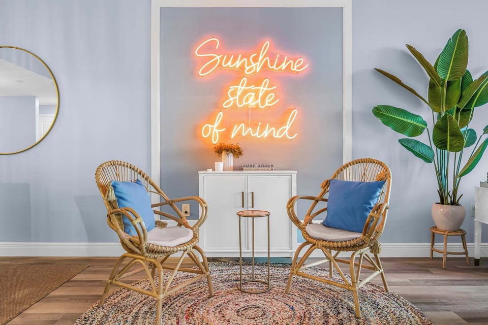 Cozy seating area with rattan chairs and a neon sign creating a relaxed atmosphere.