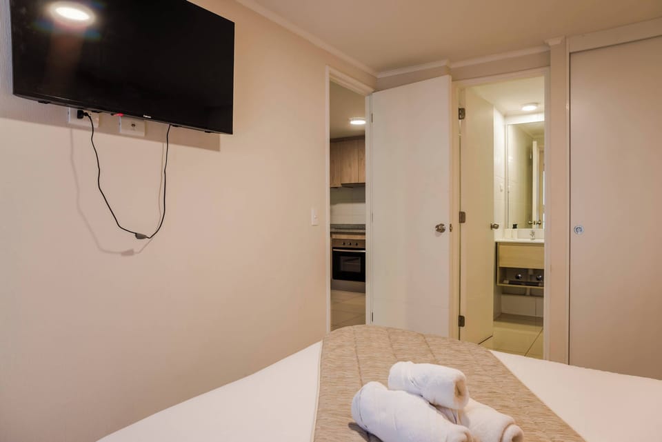 Cozy bedroom with easy access to kitchen and bathroom, featuring a wall-mounted TV for your entertainment.